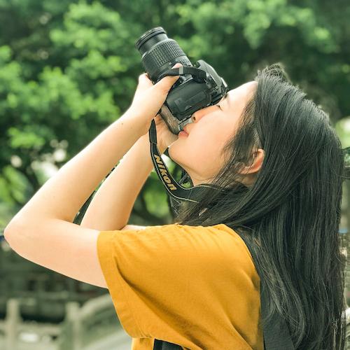 A woman points a camera to the upper left.